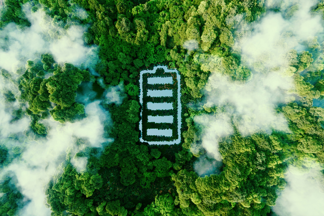 Eine Vogelperspektive zeigt einen Wald aus üppigem Grün, in dessen Mitte eine große, stilisierte Batterie angeordnet ist. Die Form ist von weißen Umrissen umgeben und steht im Kontrast zu den umgebenden Bäumen und dem leichten Nebel.