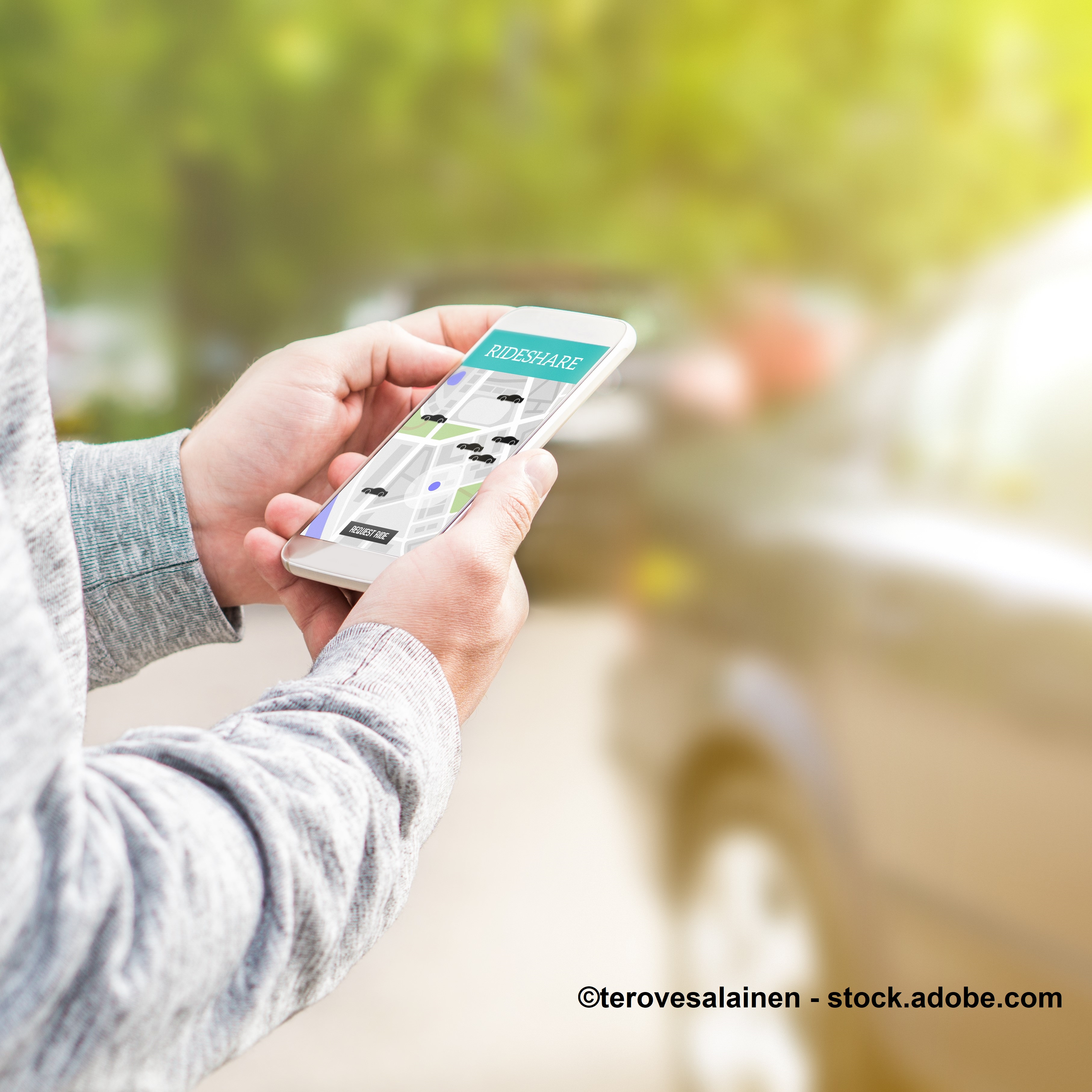 A person holds a smartphone displaying a rideshare app interface with a map showing various available cars. The background features blurred images of parked cars and greenery, suggesting an outdoor setting.