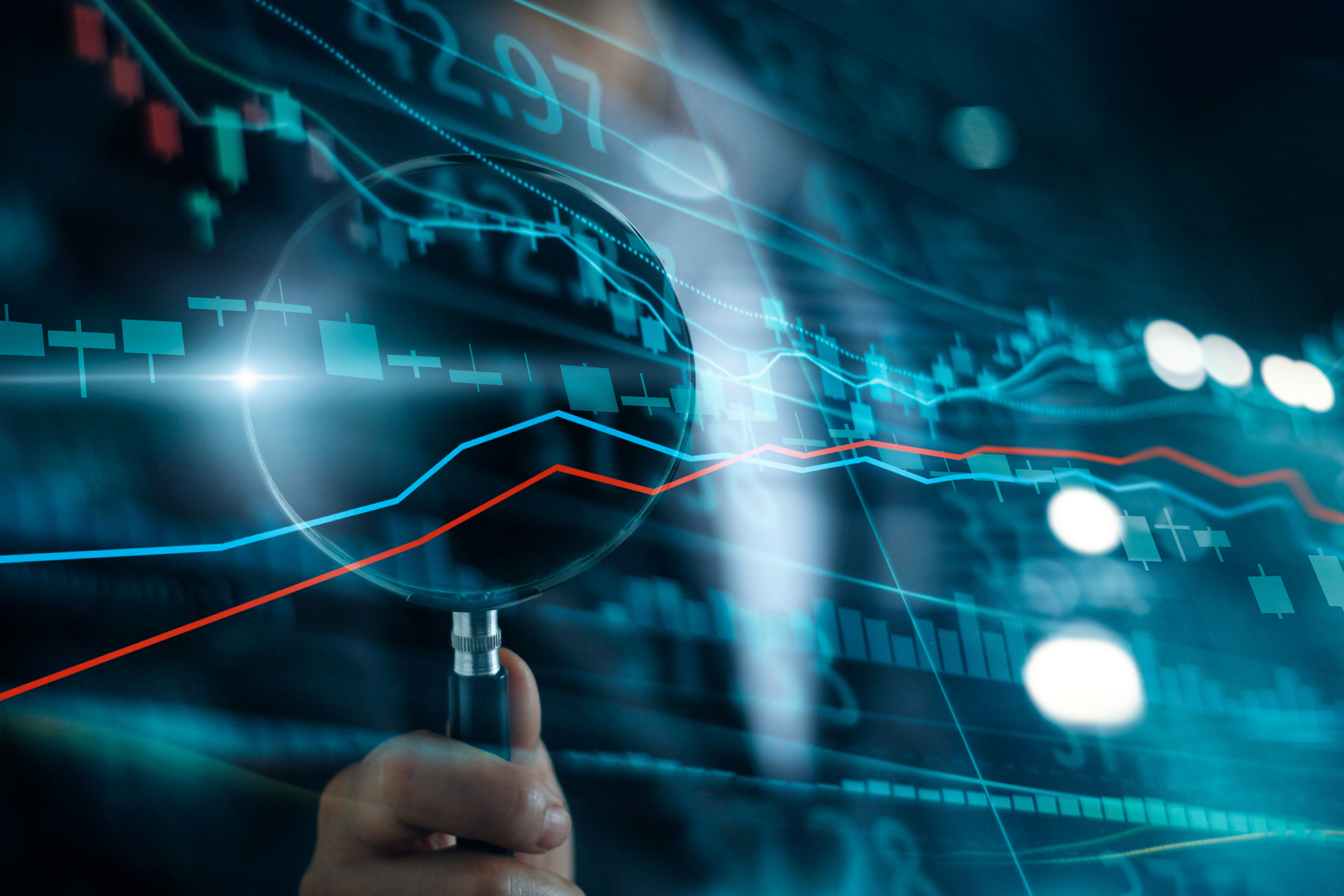 Ein Mensch hält eine Lupe über ein grafisches Diagramm mit roten und blauen Linien, die einen Aktienkurs darstellen. Im Hintergrund sind digitale Daten und Zahlen zu sehen, die die Analyse von Finanzmärkten symbolisieren.