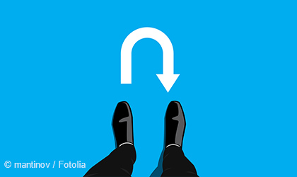 Zwei schwarze Schuhe stehen auf einem blauen Hintergrund. Über den Schuhen befindet sich ein großes, weißes U-Turn-Symbol, das zeigt, dass man sich umdrehen oder die Richtung ändern soll.