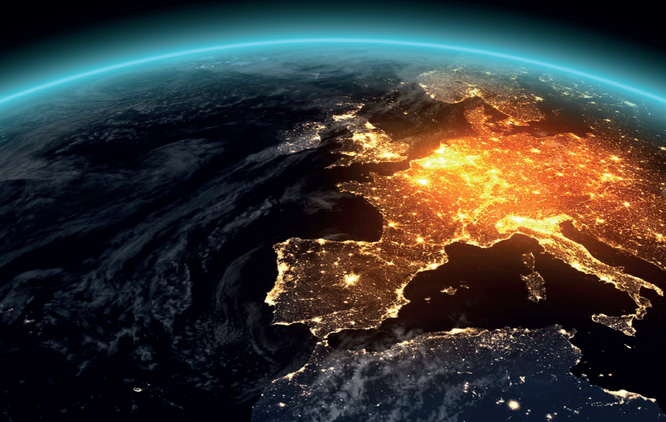 Eine Ansicht der Erde aus dem Weltraum zeigt Europa bei Nacht, beleuchtet durch Städte und menschliche Aktivitäten. Die Küstenlinien sind deutlich zu erkennen, während der Ozean im Dunkeln liegt und sich mit Wolken vermischt.
