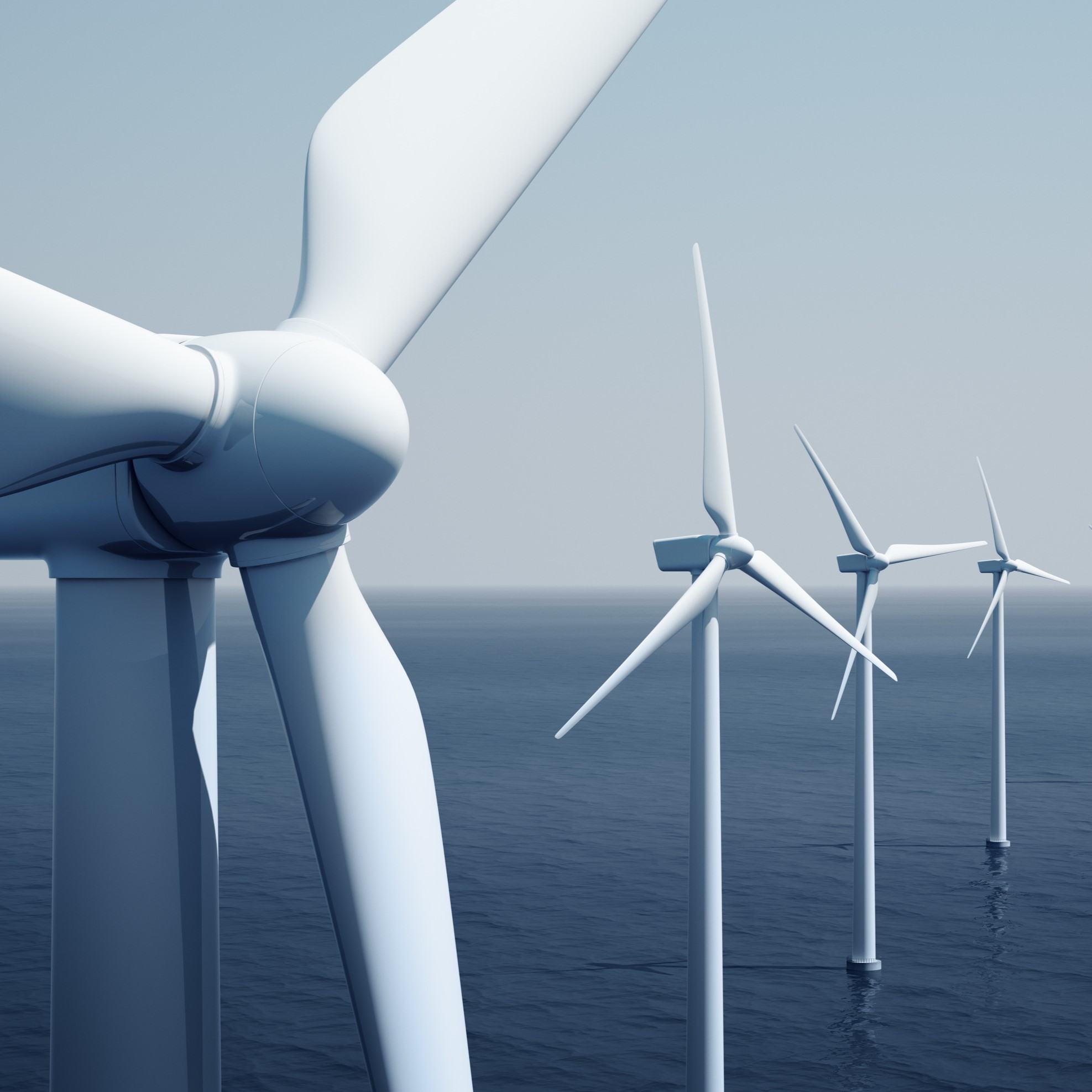 Vier große Windturbinen stehen in der Nähe des Wassers. Die Rotorblätter drehen sich, während sie Energie aus dem Wind generieren. Der Himmel ist hell und klar, was die saubere, erneuerbare Energienutzung symbolisiert.