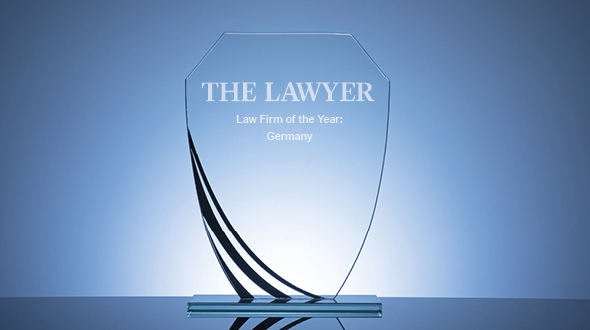 A crystal award with a modern design, inscribed with "THE LAWYER" and the title "Law Firm of the Year: Germany." The award is displayed on a smooth surface against a subtle blue background, highlighting its elegant features.