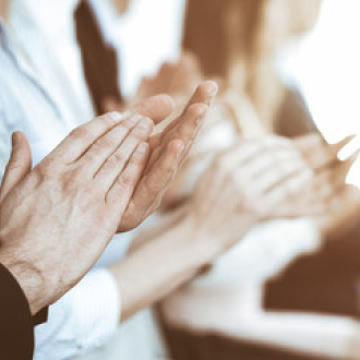 A group of hands is shown clapping together, suggesting applause or appreciation. The hands are diverse, with different skin tones and styles, symbolizing a positive response to a performance or presentation. The focus is on the act of clapping.
