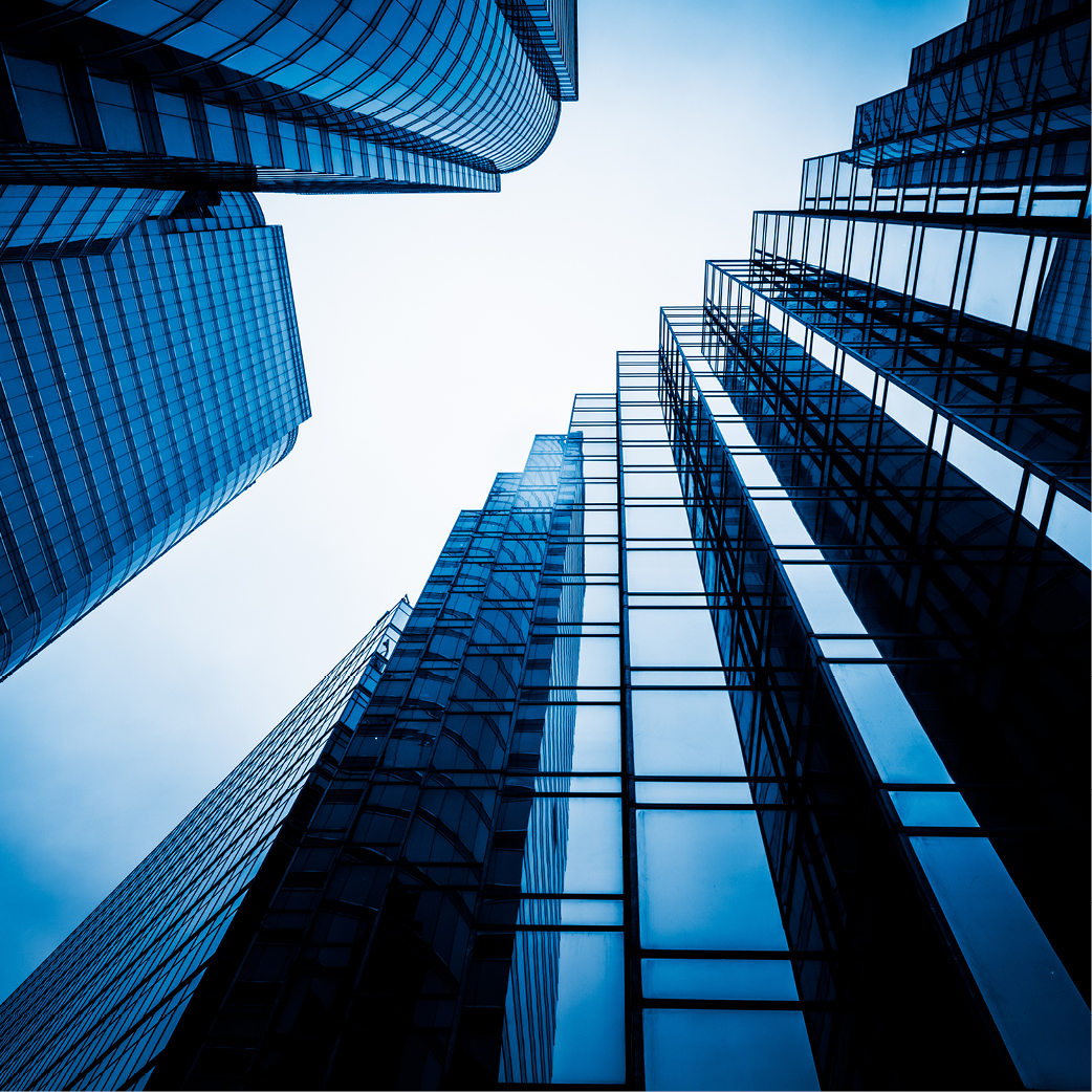 Ein Blick nach oben auf moderne Wolkenkratzer aus Glas und Stahl, die in einem hellen Blauton reflektieren. Die Gebäude ziehen sich in die Höhe, umgeben von einem klaren Himmel. Die Perspektive vermittelt ein Gefühl von Größe und urbaner Architektur.
