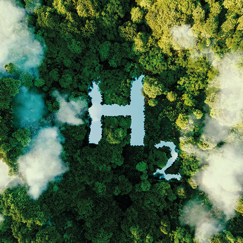 Aerial view of a dense green forest with a water surface prominently displaying the chemical formula "H2" for hydrogen. Light clouds partially obscure parts of the forest, emphasizing the lush vegetation surrounding the water.