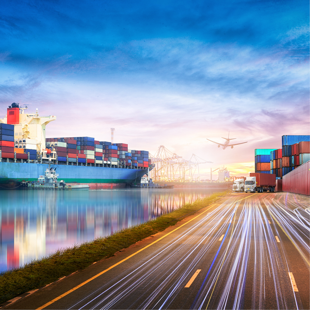 Ein großer Frachter mit Containern liegt im Hafen, während sich ein Lkw entlang einer Straße bewegt. Im Hintergrund sind Kräne und ein Flugzeug am Himmel zu sehen. Die Szene vermittelt eine geschäftige Hafenatmosphäre.