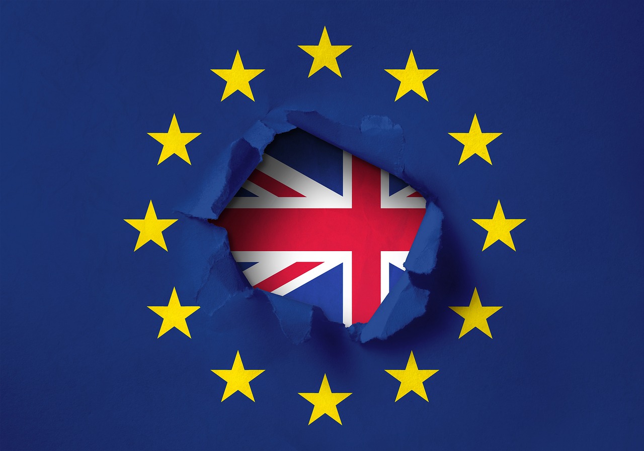 Ein Riss in einer blauen Flagge mit gelben Sternen zeigt die britische Flagge im Hintergrund. Das Bild symbolisiert den Austritt des Vereinigten Königreichs aus der Europäischen Union.