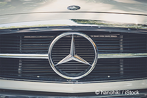 Das Bild zeigt den Kühlergrill eines Autos mit einem auffälligen Mercedes-Benz-Stern-Emblem in der Mitte. Der grill hat vertikale Lamellen und glänzende Oberflächen, die das Markenlogo betonen. Die Farben sind überwiegend silber und schwarz.