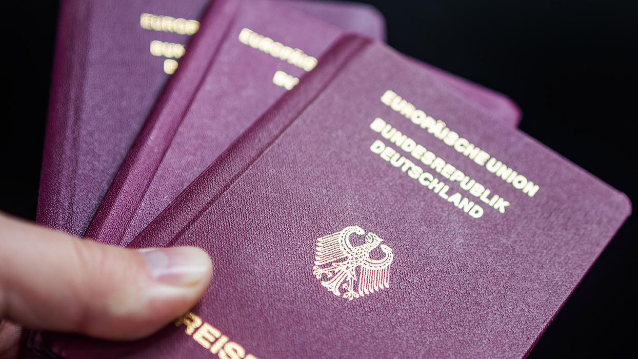 A hand holds multiple burgundy passports, displaying the words "Europäische Union" and "Bundesrepublik Deutschland" in gold lettering. The design features the German eagle emblem, symbolizing the document's official status. The focus is on the passports, suggesting travel or identification purposes.