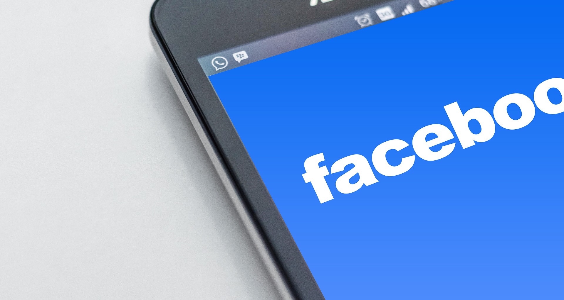 Ein Smartphone-Bildschirm zeigt das Facebook-Logo auf einem blauen Hintergrund. Das Logo ist in großen, weißen Buchstaben dargestellt und nimmt einen zentralen Platz auf dem Bildschirm ein.