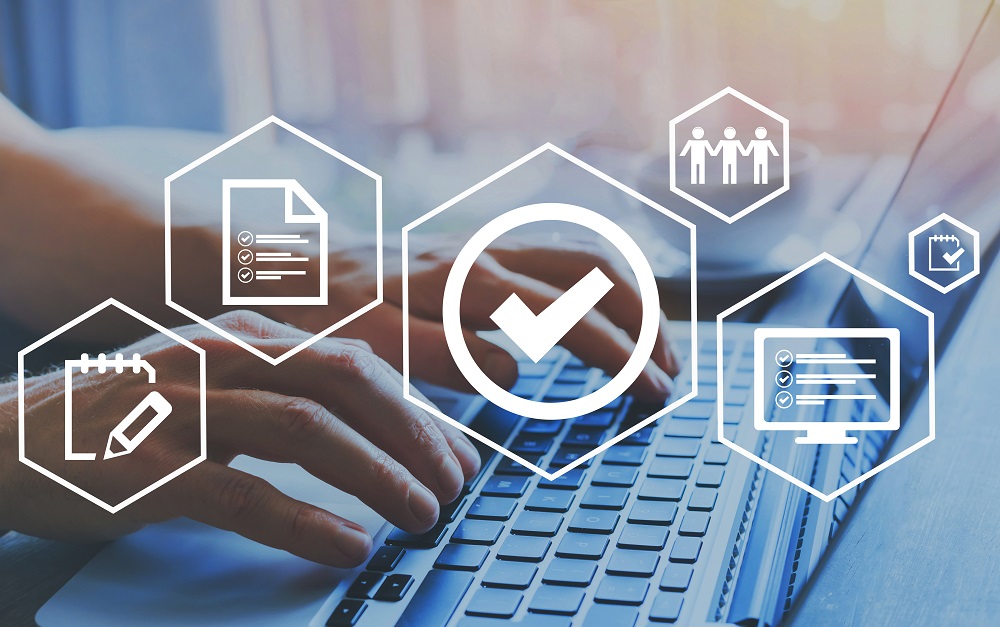 A close-up of hands typing on a laptop keyboard, surrounded by icons representing tasks, collaboration, completion, and digital management. The central icon shows a checkmark, indicating successful completion or approval. The background is soft and professional, suggesting a productive work environment.