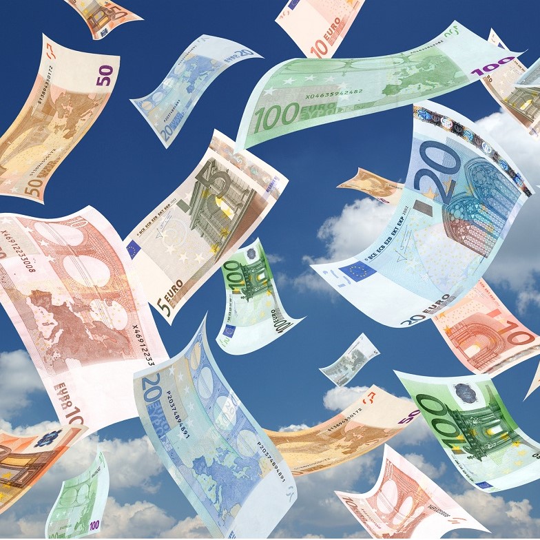 Verschiedene Euro-Scheine in unterschiedlichen Werten (5, 10, 20, 50 und 100 Euro) schweben vor einem blauen Himmel mit wenigen Wolken. Die Banknoten sind wild verteilt und vermitteln das Gefühl von Freiheit und Fülle.