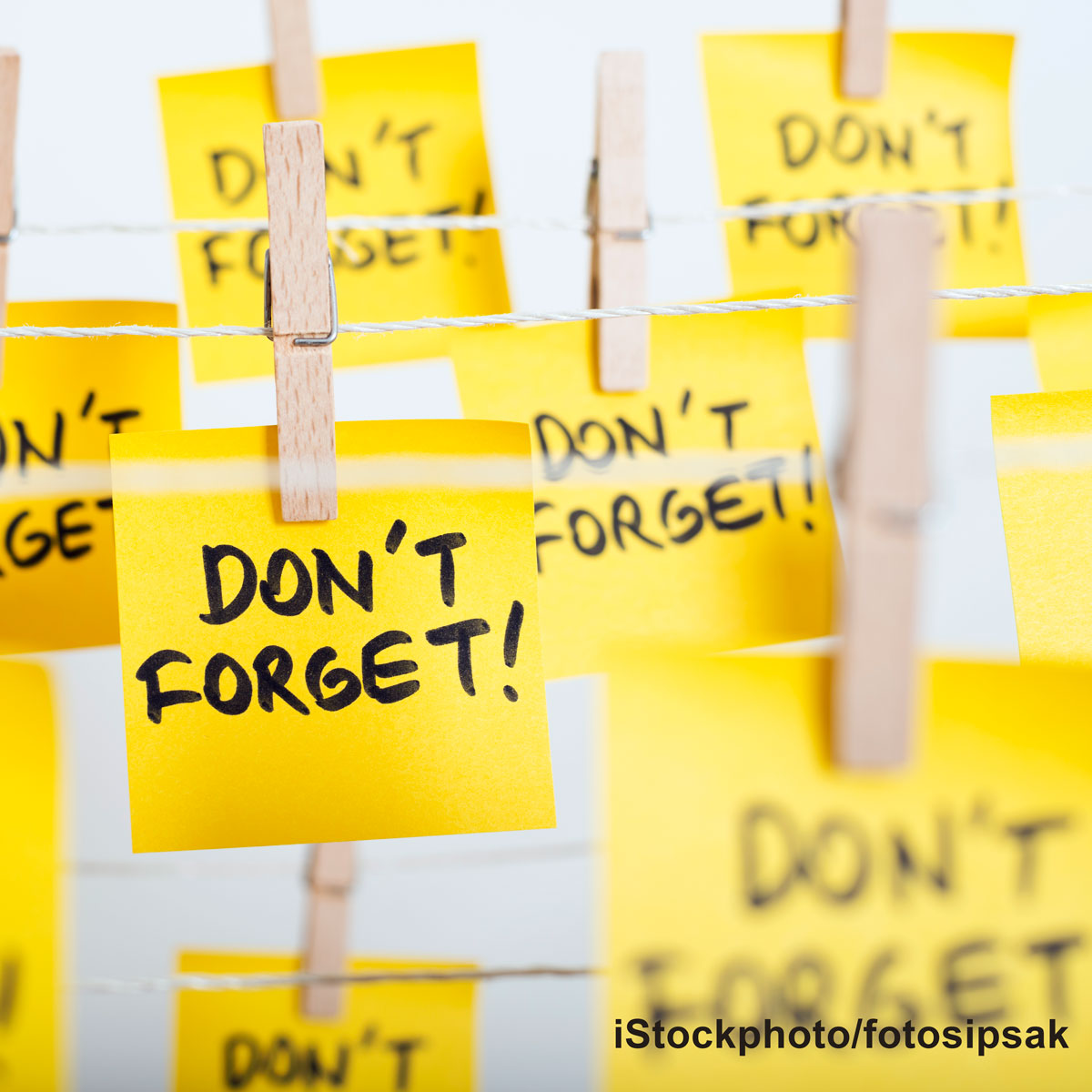 A collection of bright yellow sticky notes hanging on a string, each with the message "Don't forget!" written in bold black letters, emphasizing reminders and important tasks.