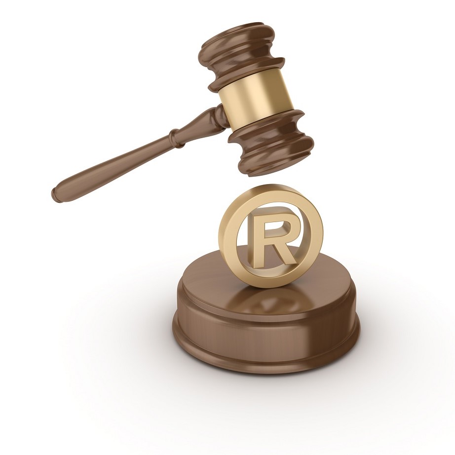 Ein Richterhammer schwebt über einem goldenen Registrierungszeichen (R) auf einem runden Sockel. Das Bild symbolisiert rechtliche Aspekte des Markenschutzes und die Bedeutung eingetragener Marken.