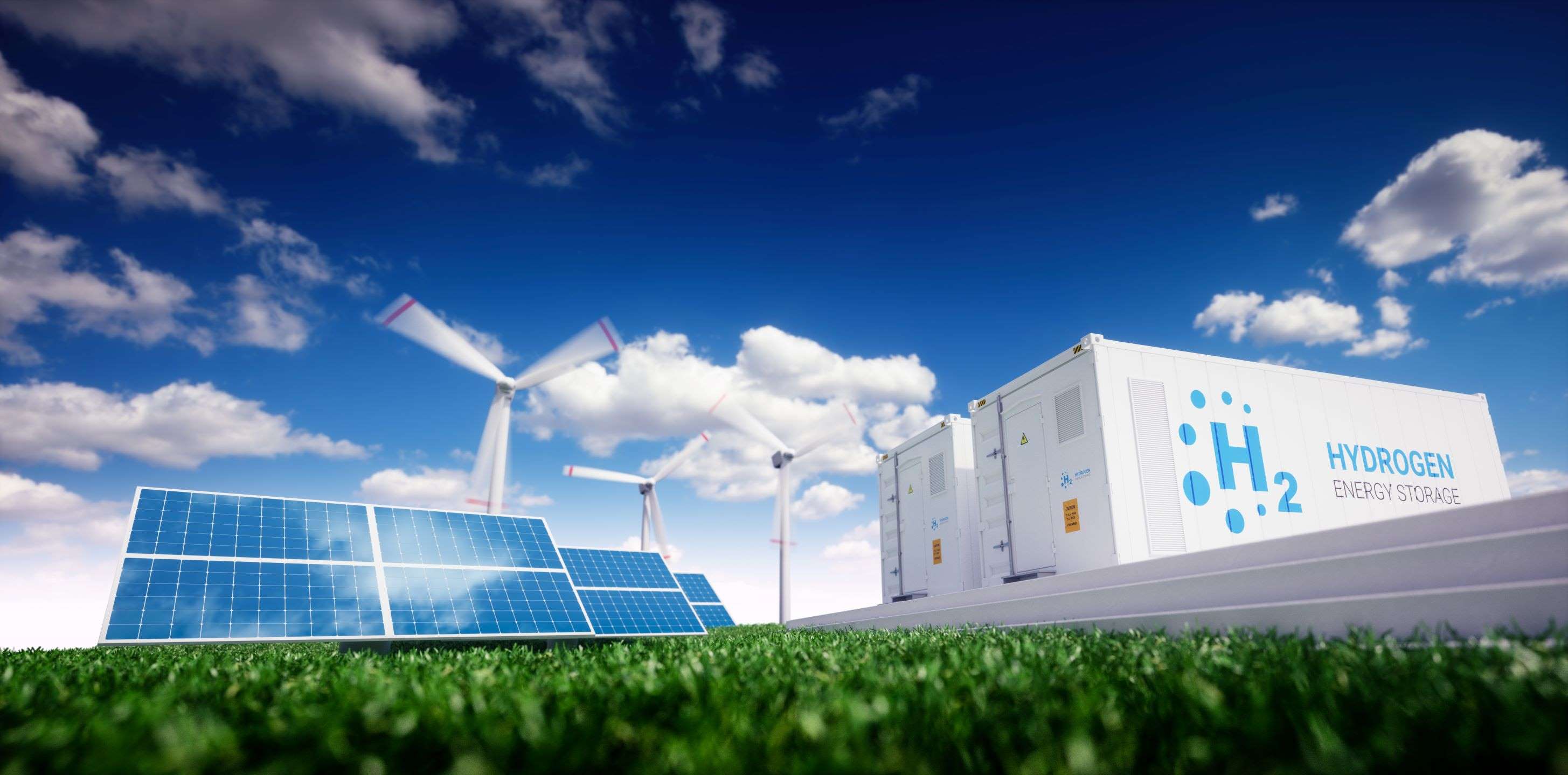 Ein Bild zeigt eine grüne Wiese mit Solarpanelen und Wasserstoffspeicher-Einheiten. Im Hintergrund sind Windkraftanlagen vor einem klaren, blauen Himmel mit einigen Wolken sichtbar. Das Bild vermittelt ein Gefühl von nachhaltiger Energie und moderner Technologie.